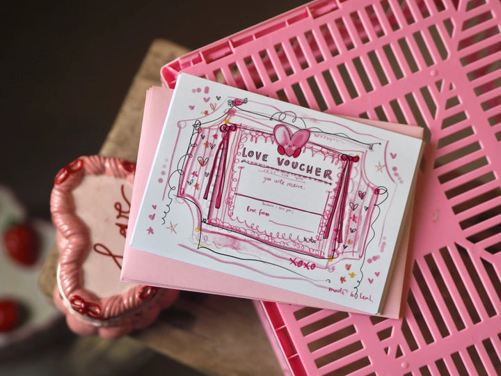 Love voucher card with decorative elements on a pink surface